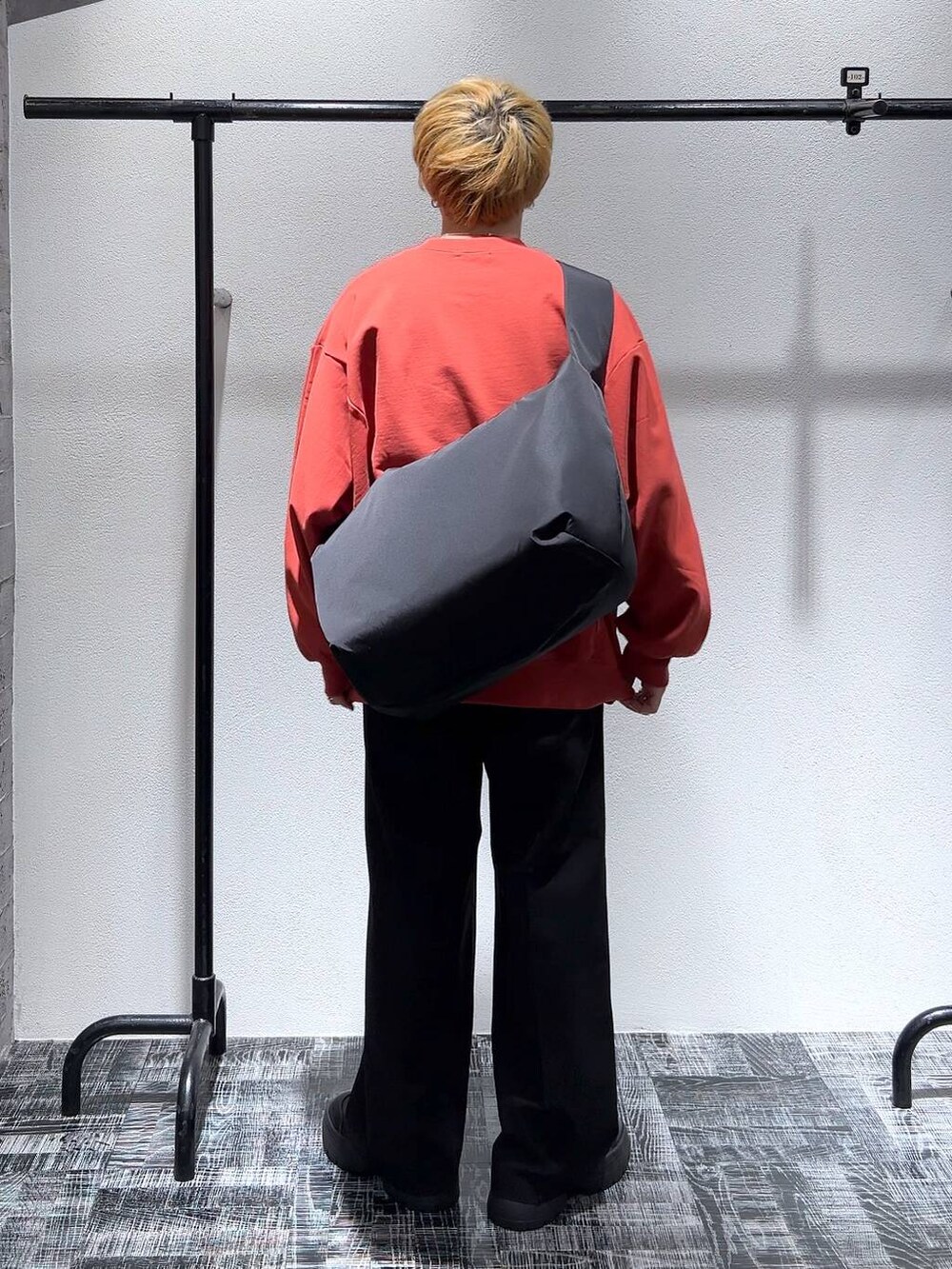 ブラック系のショルダーバッグ、オレンジ系のスウェット、ブラック系のブーツを着用したメンズの冬コーディネートの4枚目の写真