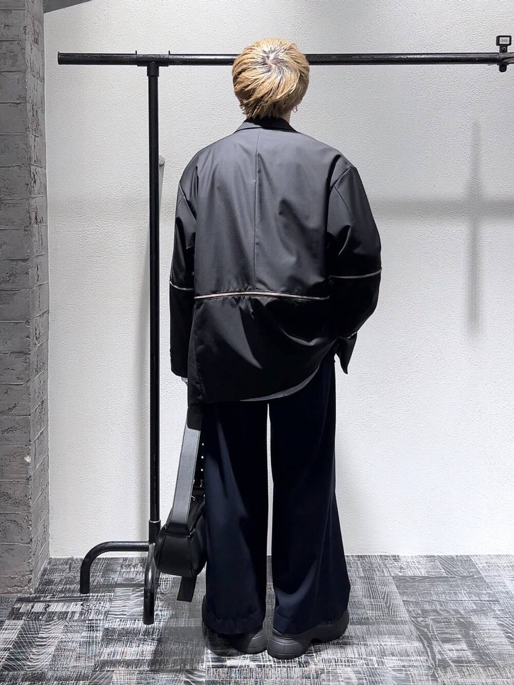 ブラック系のスニーカー、ブルー系のスラックス、ブラック系のショルダーバッグを着用したメンズの春コーディネートの4枚目の写真