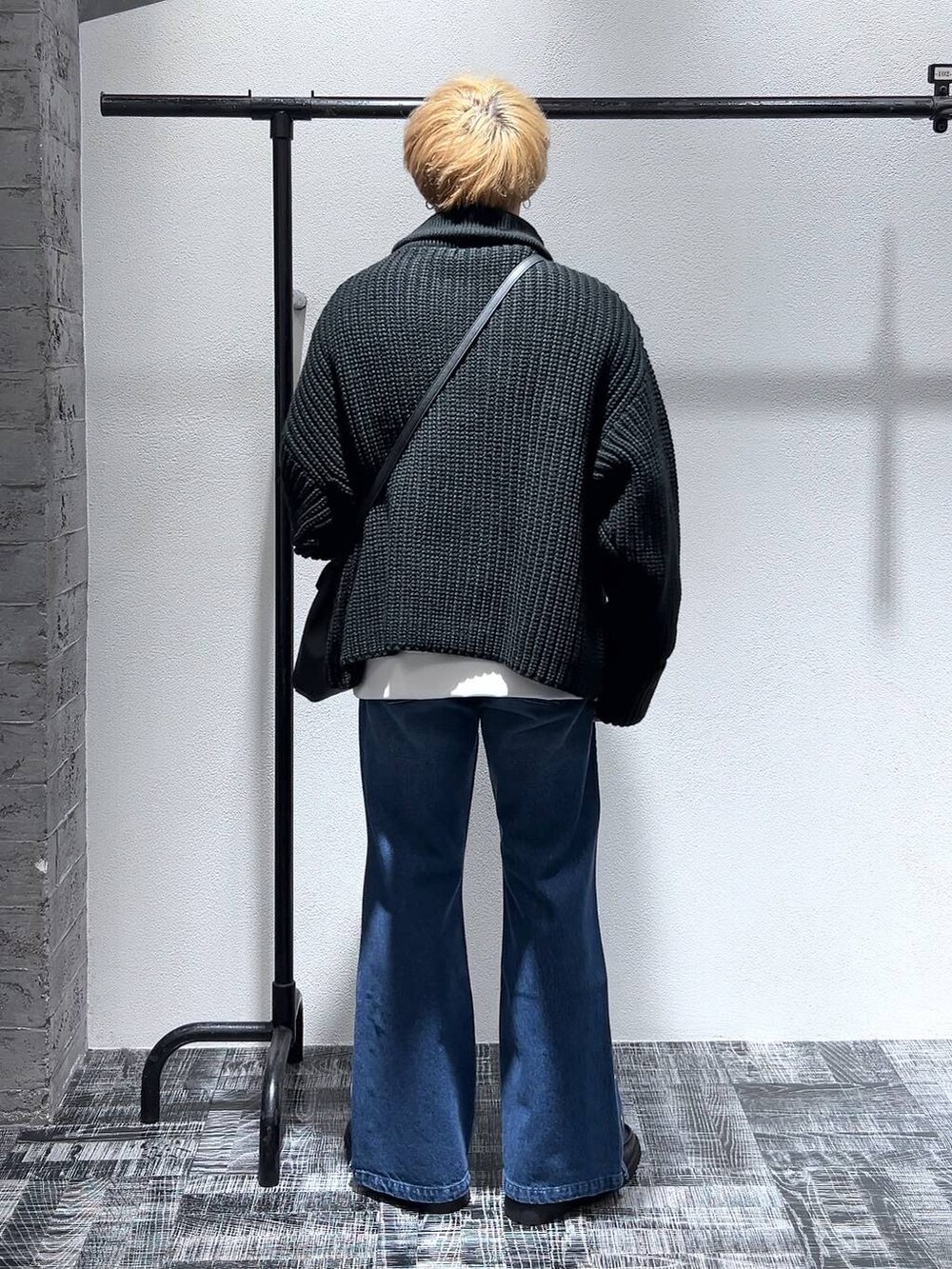 ブルー系のデニムパンツ、ブラック系のショルダーバッグ、ブラック系のドレスシューズを着用したメンズの冬コーディネートの4枚目の写真