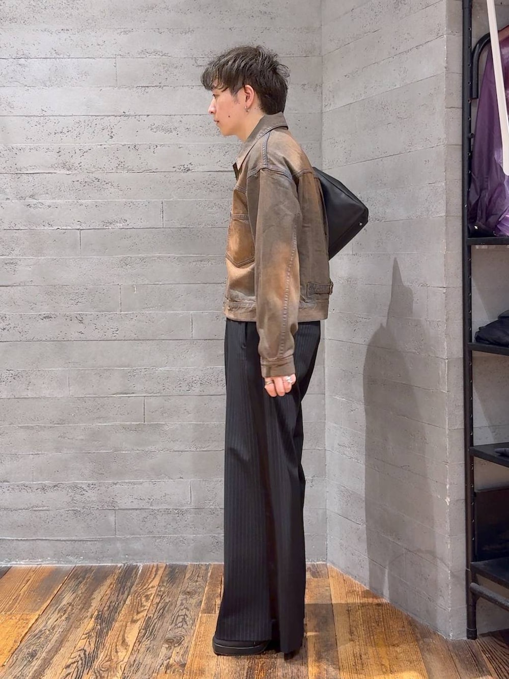 ブラウン系のデニムジャケット、ブラック系のスラックス、ブラック系のTシャツ/カットソーを着用したメンズの夏コーディネートの4枚目の写真