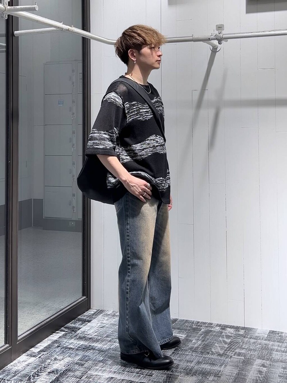ブルー系のデニムパンツ、ブラック系のショルダーバッグ、ブラック系のニット/セーターを着用したメンズの夏コーディネートの5枚目の写真