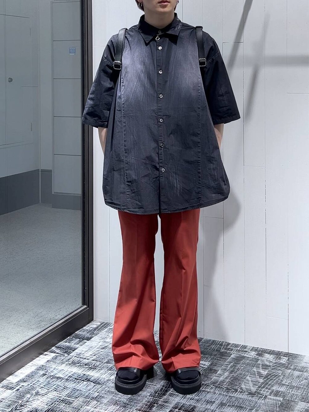 ブラック系のサンダル、ブラック系のショルダーバッグ、オレンジ系のスラックスを着用したメンズの春コーディネートの2枚目の写真