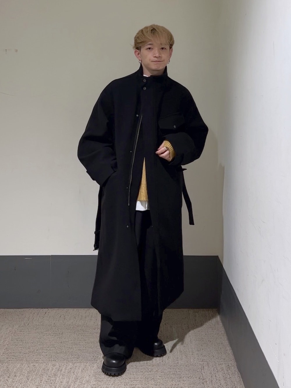 イエロー系のニット/セーター、ホワイト系のシャツ/ブラウス、ブラック系のステンカラーコートを着用したメンズの秋コーディネートの3枚目の写真