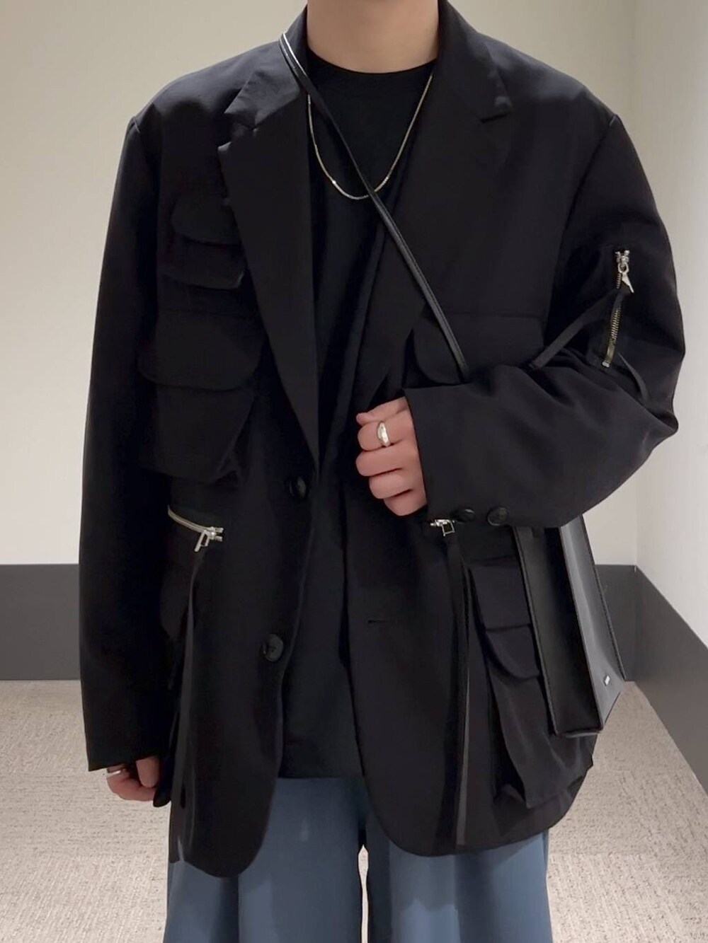 ブラック系のテーラードジャケット、ブラック系のTシャツ/カットソー、ブラック系のショルダーバッグを着用したメンズの冬コーディネートの5枚目の写真