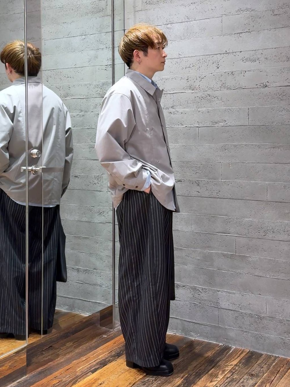 ブラック系のトートバッグ、ブラック系のブーツ、ブラック系のスラックスを着用したメンズの春コーディネートの2枚目の写真