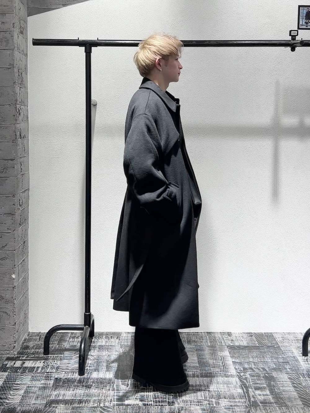 ブラック系のデニムパンツ、ブラック系のステンカラーコート、ブラック系のショルダーバッグを着用したメンズの秋コーディネートの3枚目の写真