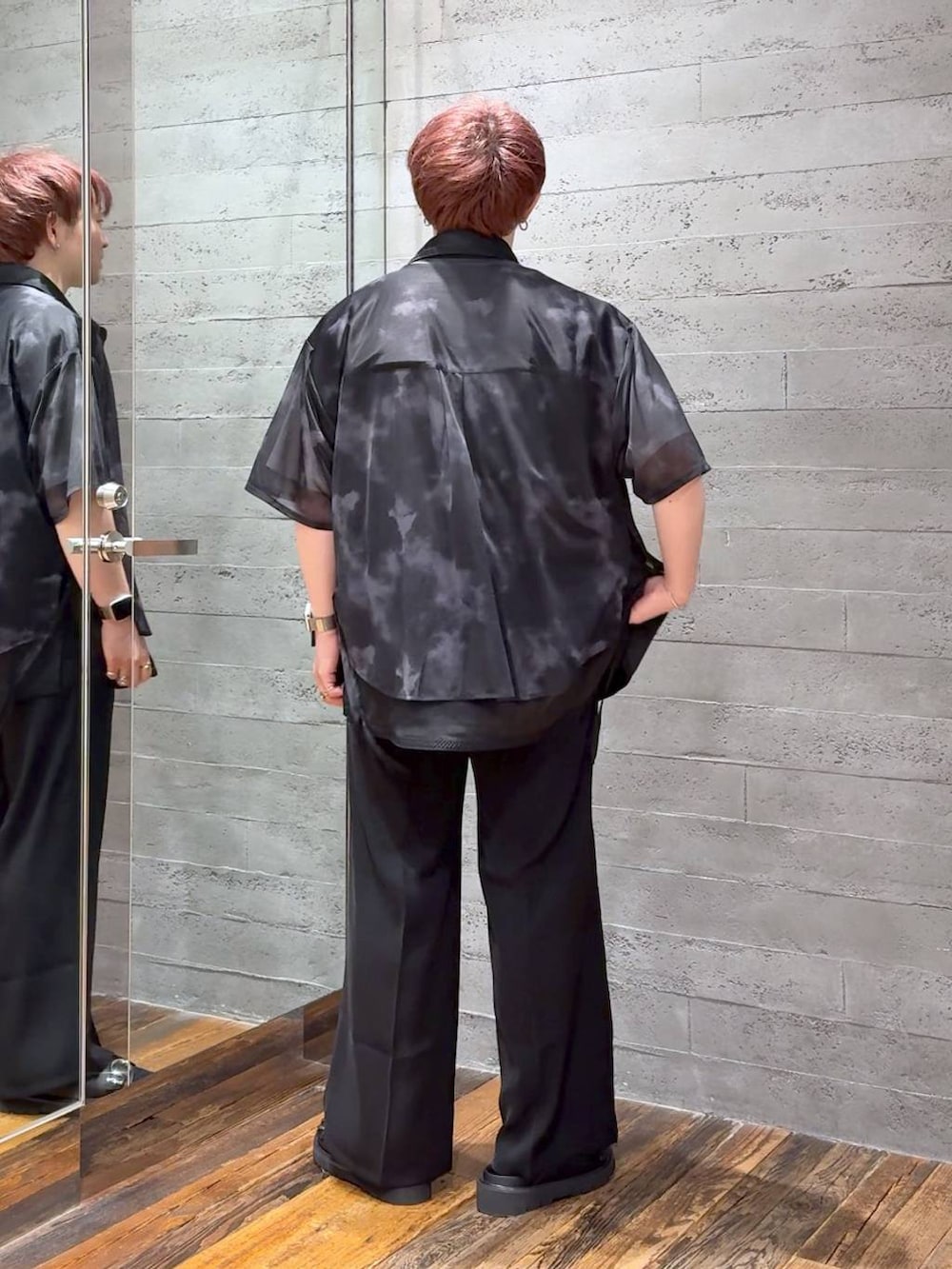 ブラック系のスラックス、ホワイト系のTシャツ/カットソー、ブラック系のサンダルを着用したメンズの夏コーディネートの3枚目の写真