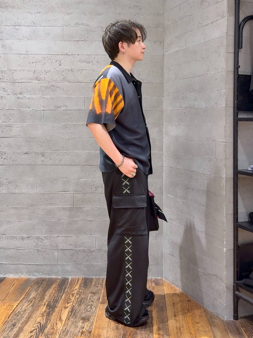 ブラック系のカーゴパンツ、ブラック系のニット/セーター、ブラック系のサンダルを着用したメンズの夏コーディネートの2枚目の写真