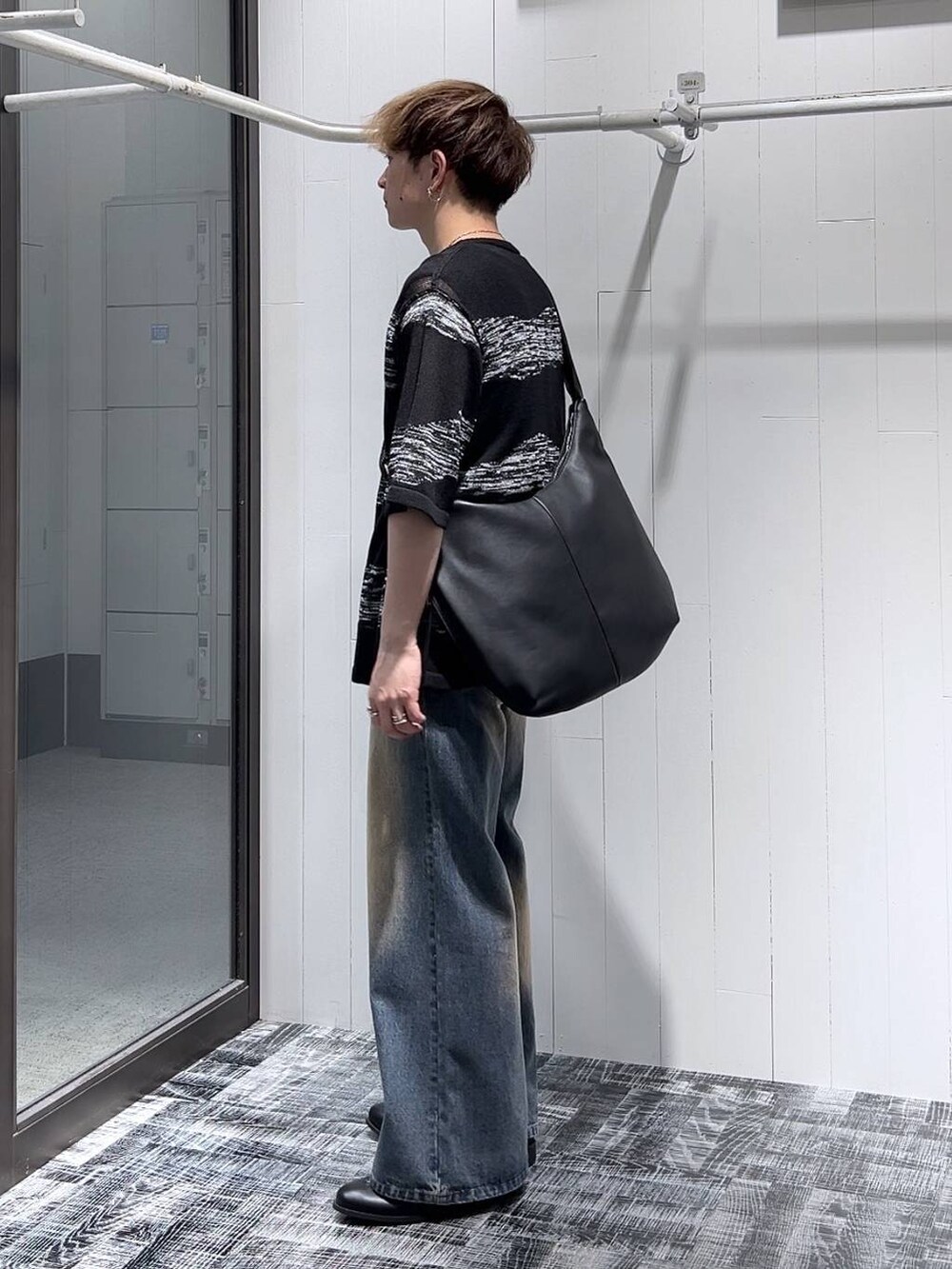 ブルー系のデニムパンツ、ブラック系のショルダーバッグ、ブラック系のニット/セーターを着用したメンズの夏コーディネートの4枚目の写真