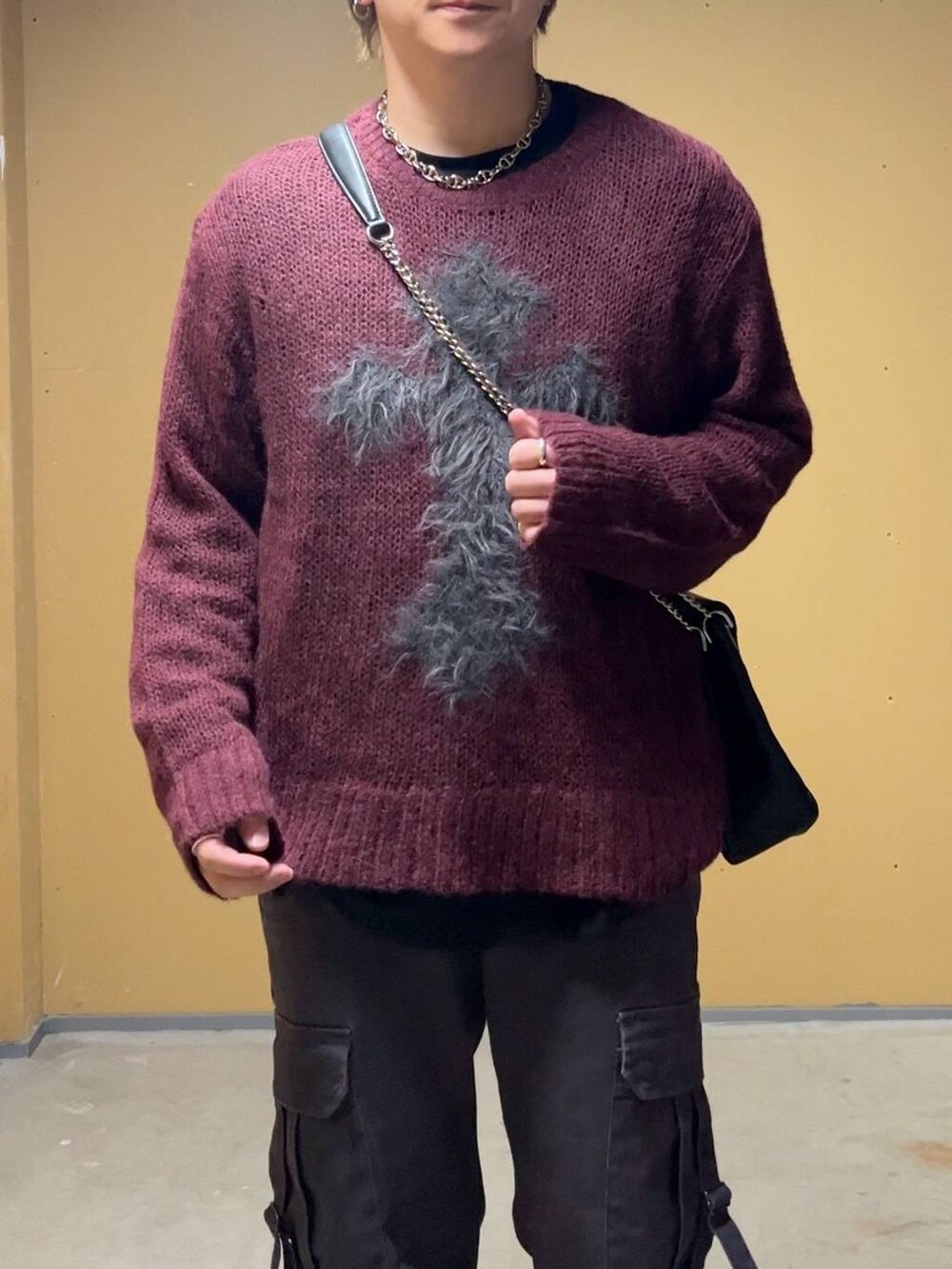 ブラック系のドレスシューズ、ブラック系のショルダーバッグ、レッド系のニット/セーターを着用したメンズの春コーディネートの5枚目の写真