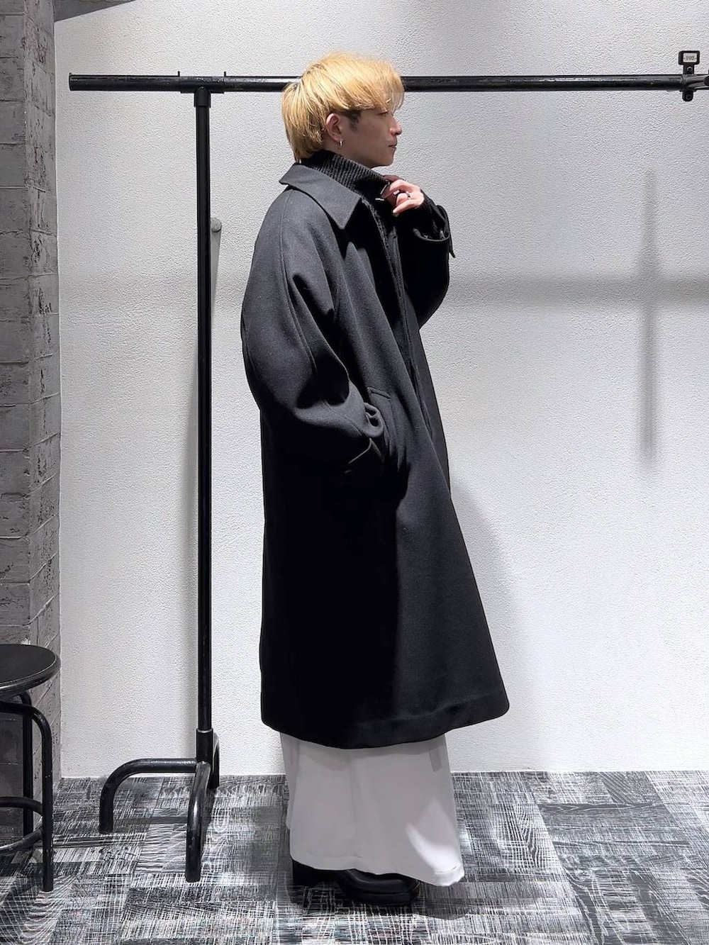 ブラック系のブーツ、ブラック系のステンカラーコート、ブラック系のショルダーバッグを着用したメンズの冬コーディネートの3枚目の写真