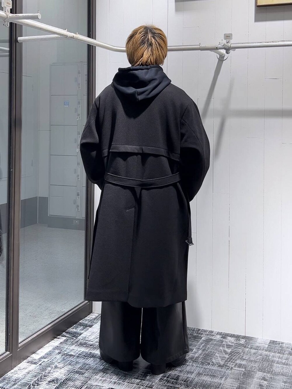 ブラック系のステンカラーコート、ブラック系のその他パンツ、ブラック系のパーカーを着用したメンズの冬コーディネートの3枚目の写真