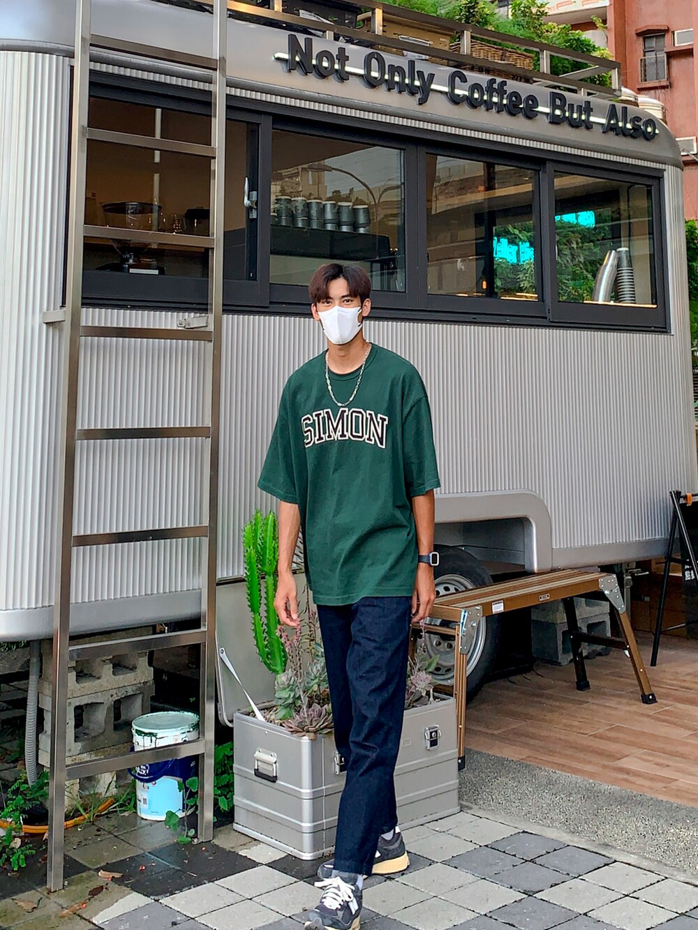 グリーン系のTシャツ/カットソー、ブルー系のチノパンツ、グレー系のスニーカーを着用したメンズの夏コーディネートの2枚目の写真