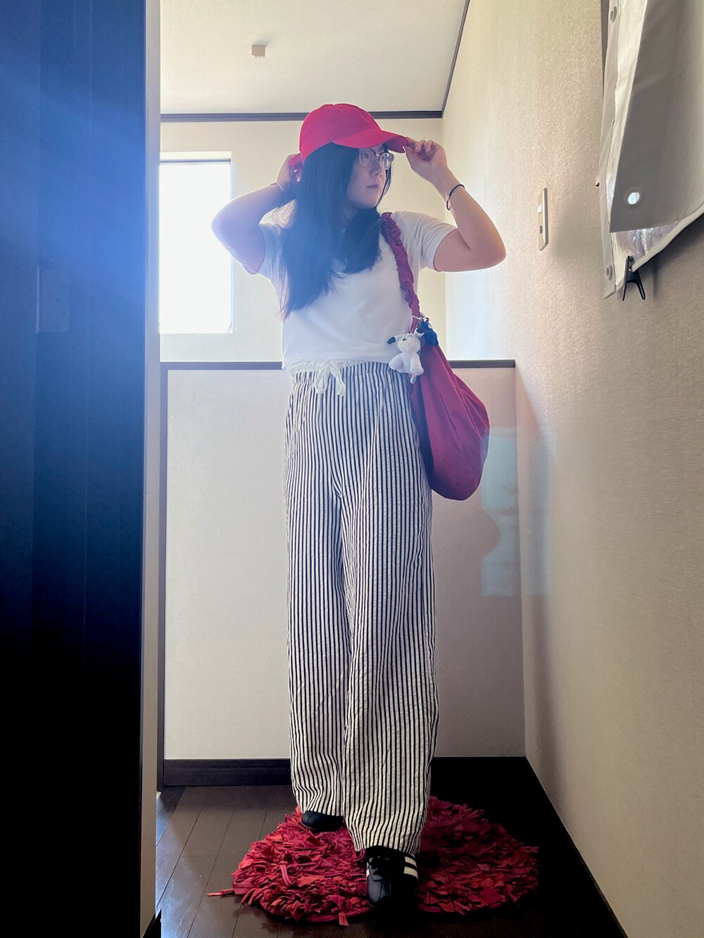 ブラック系のスニーカー、ホワイト系のTシャツ/カットソー、レッド系のショルダーバッグを着用したレディースの夏コーディネートの3枚目の写真