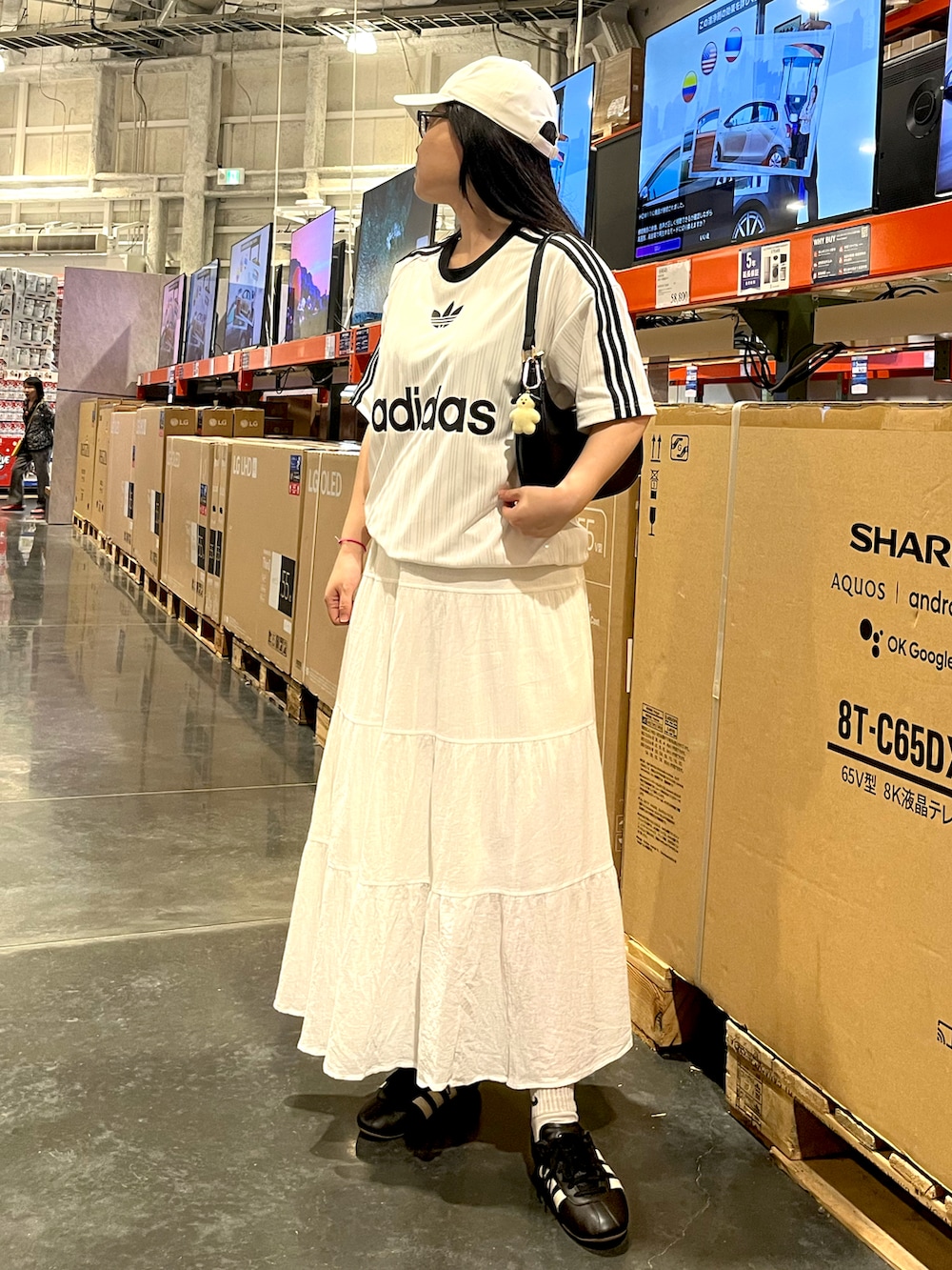 ブラック系のスニーカー、ホワイト系のスカート、ホワイト系のTシャツ/カットソーを着用したレディースの夏コーディネートの2枚目の写真