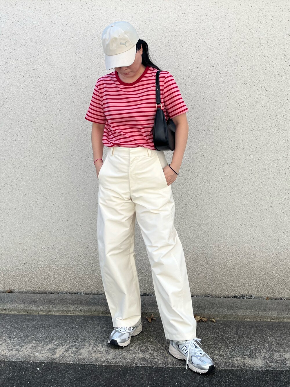 ブラック系のパンツ、シルバー系のスニーカー、ベージュ系のキャップを着用したレディースの秋コーディネートの2枚目の写真