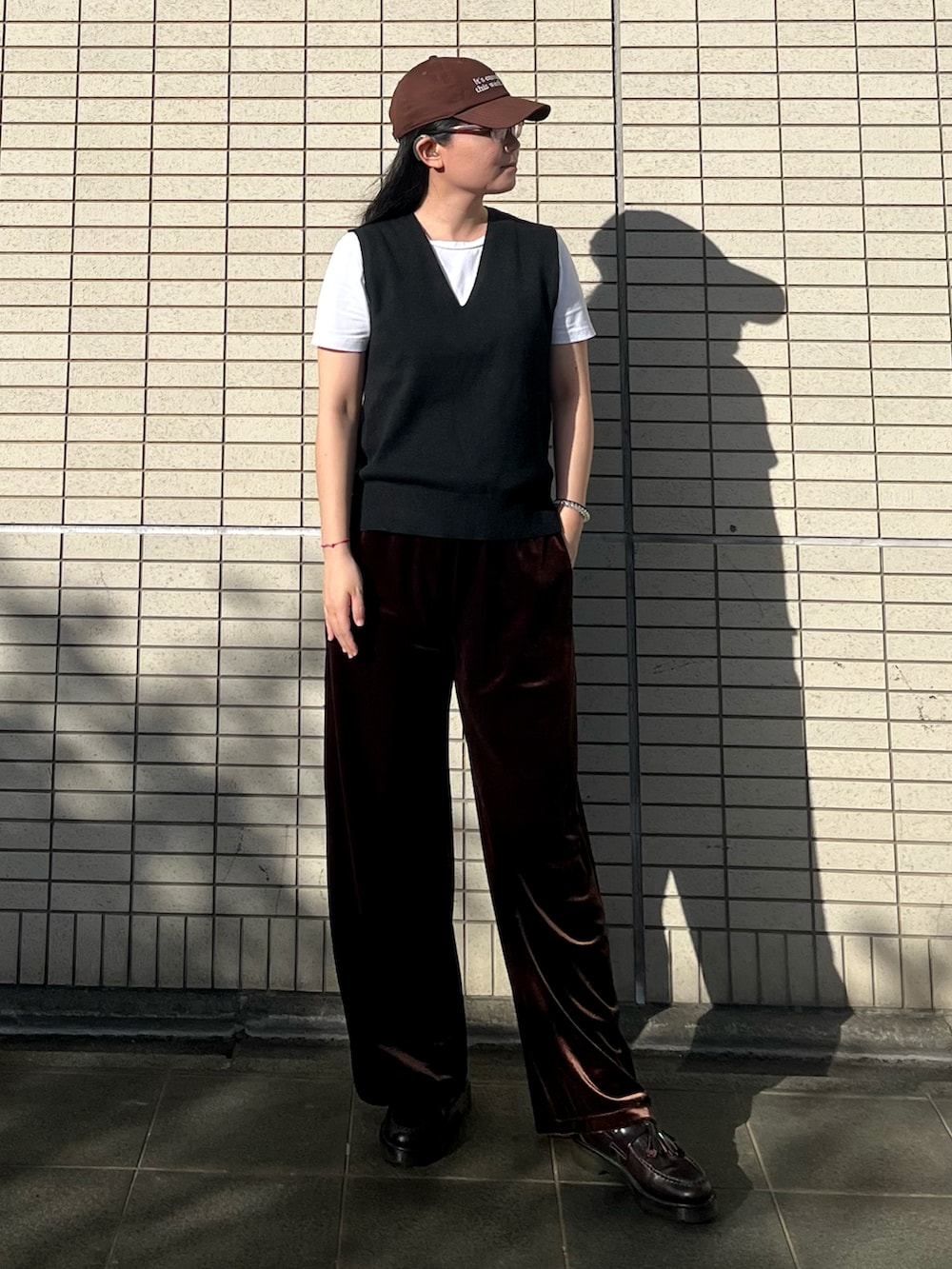 ブラック系のベスト、ブラウン系のパンツ、ブラウン系のローファーを着用したレディースの秋コーディネートの2枚目の写真