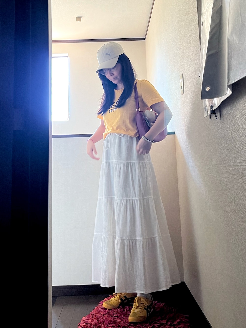 イエロー系のスニーカー、イエロー系のTシャツ/カットソー、ホワイト系のスカートを着用したレディースの夏コーディネートの2枚目の写真
