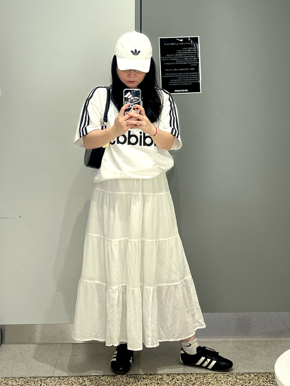 ブラック系のスニーカー、ホワイト系のスカート、ホワイト系のTシャツ/カットソーを着用したレディースの夏コーディネートの5枚目の写真