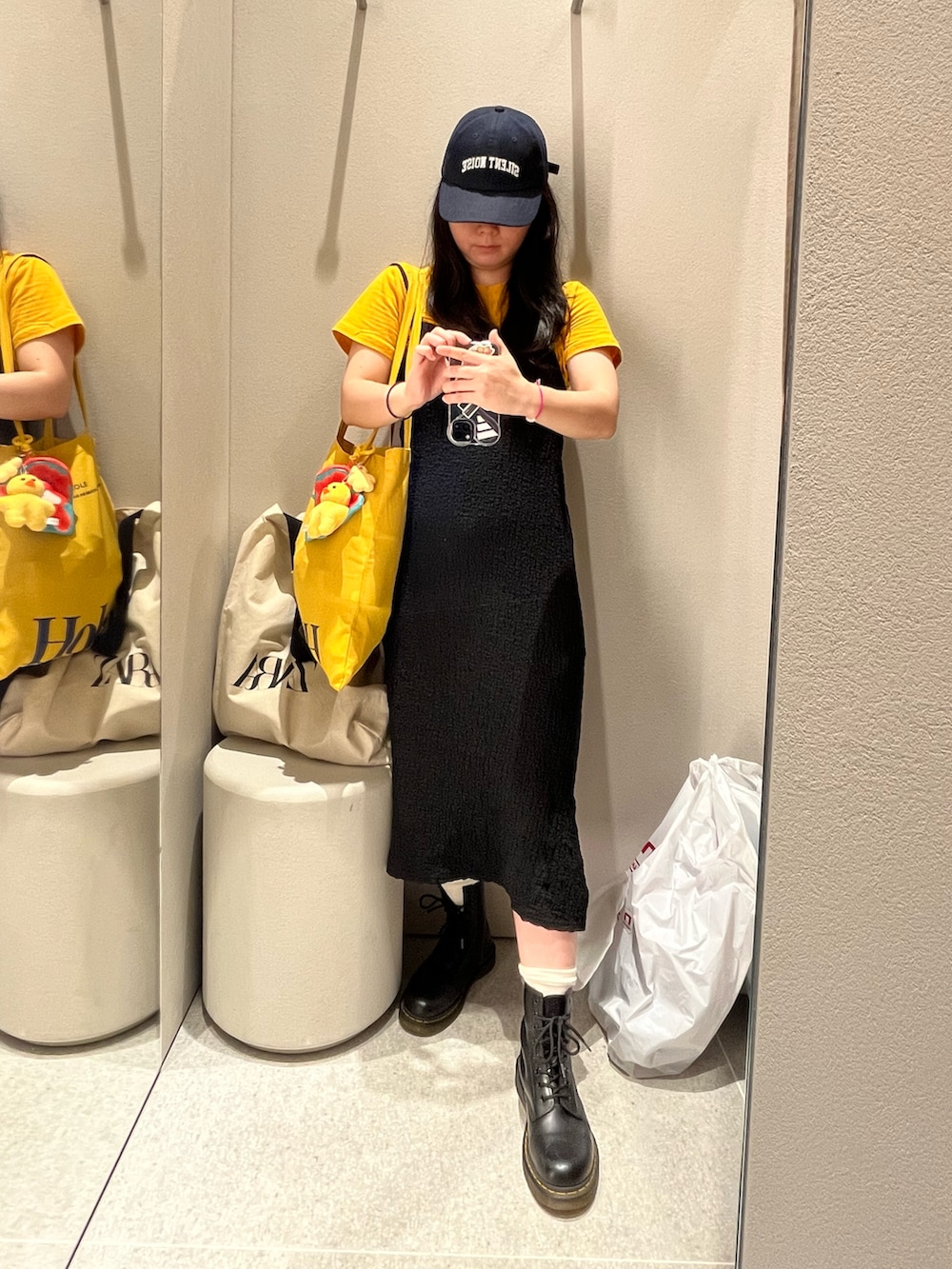 イエロー系のトートバッグ、ブラック系のブーツ、イエロー系のTシャツ/カットソーを着用したレディースの夏コーディネートの2枚目の写真