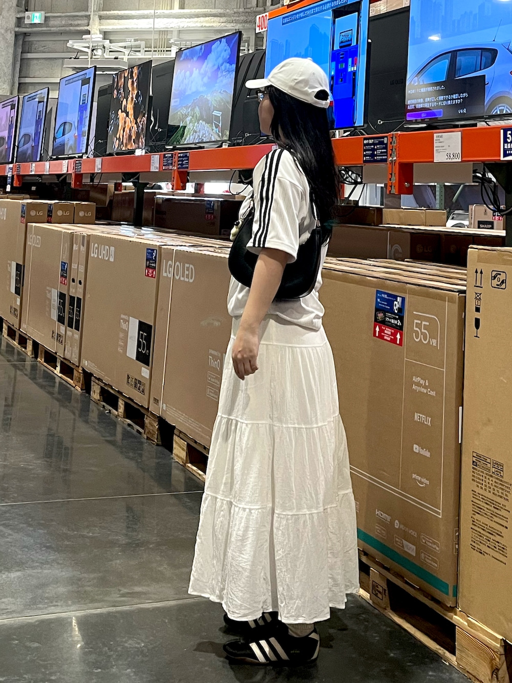 ブラック系のスニーカー、ホワイト系のスカート、ホワイト系のTシャツ/カットソーを着用したレディースの夏コーディネートの3枚目の写真