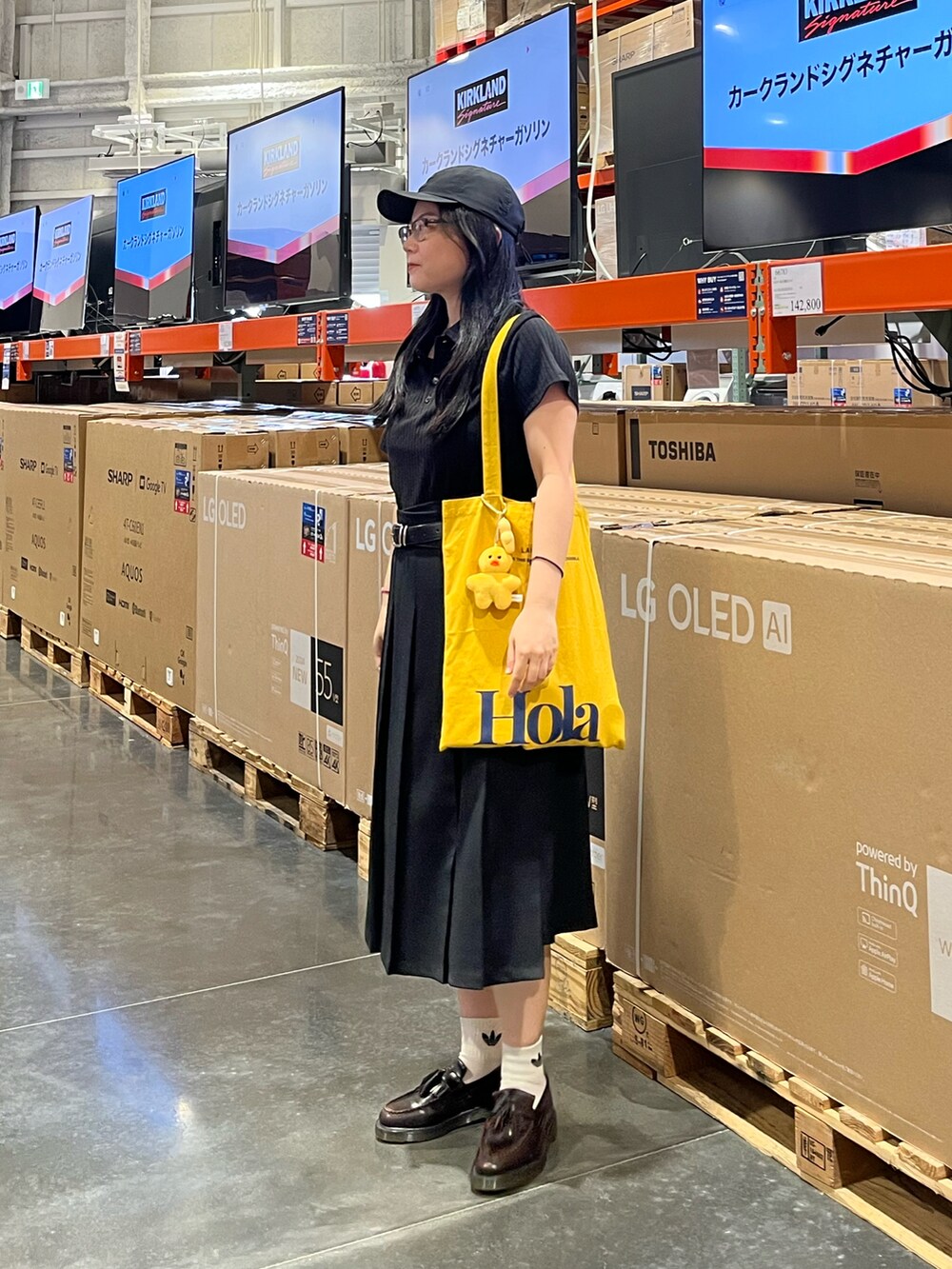 イエロー系のトートバッグ、ブラウン系のローファー、ブラック系のポロシャツを着用したレディースの夏コーディネートの3枚目の写真