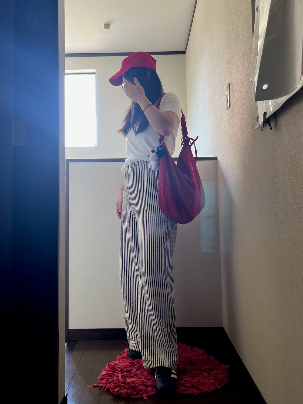 ブラック系のスニーカー、ホワイト系のTシャツ/カットソー、レッド系のショルダーバッグを着用したレディースの夏コーディネートの2枚目の写真