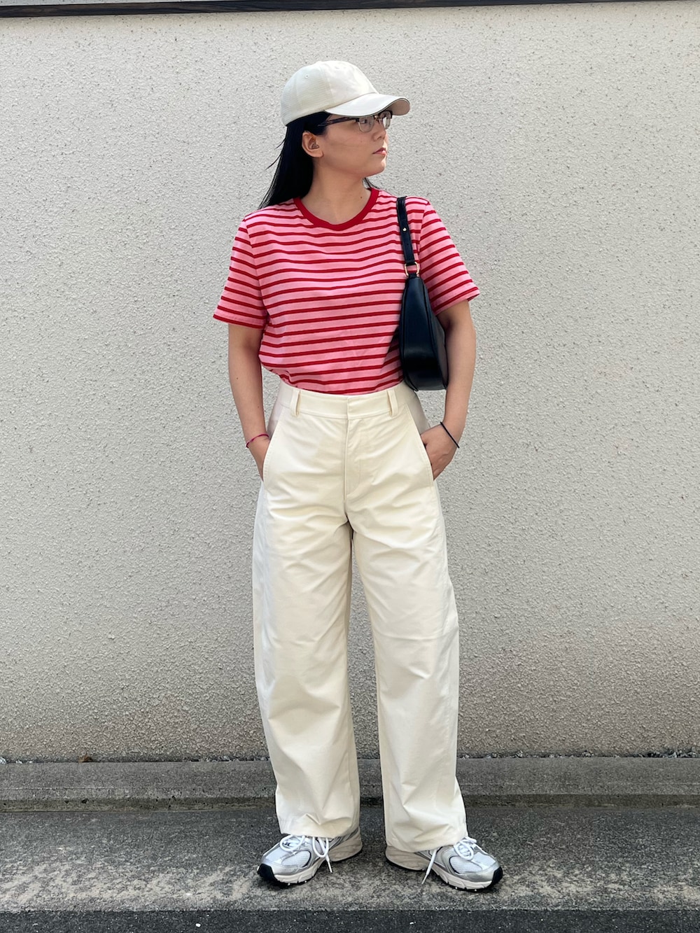 ブラック系のパンツ、シルバー系のスニーカー、ベージュ系のキャップを着用したレディースの秋コーディネートの3枚目の写真