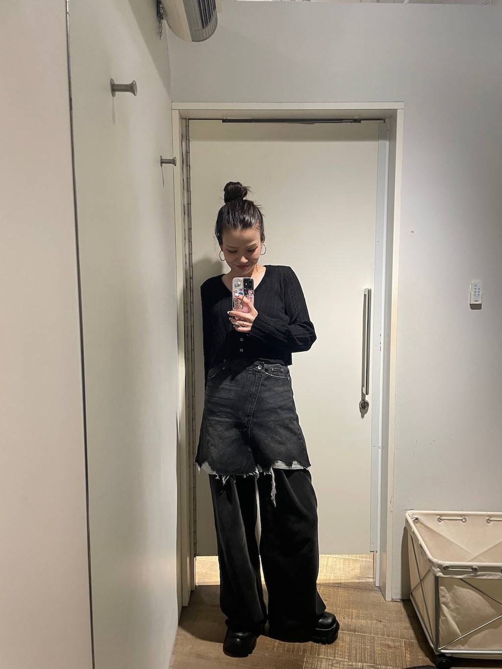 グレー系のデニムパンツ、ブラック系のカーディガン/ボレロ、ブラック系のデニムスカートを着用したレディースの秋コーディネートの2枚目の写真