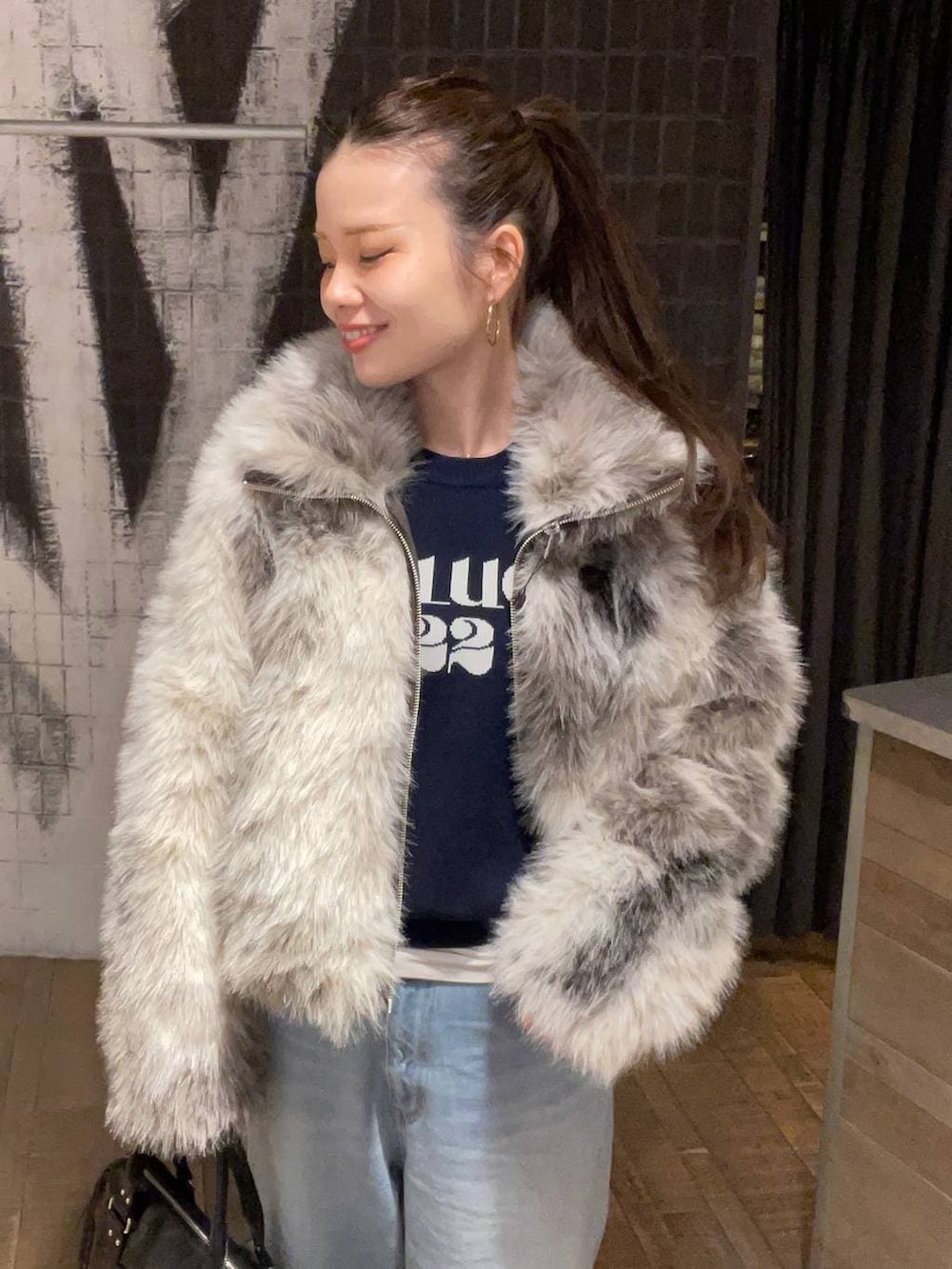 グレー系のブルゾン、ブラック系のボストンバッグ、ブルー系のニット/セーターを着用したレディースの冬コーディネートの2枚目の写真