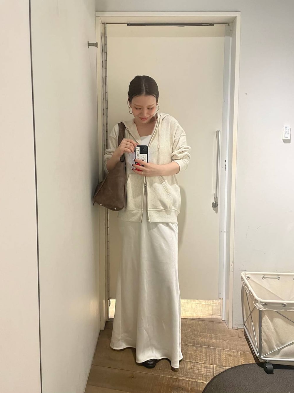 ベージュ系のパーカー、ホワイト系のキャミソール、ホワイト系のスカートを着用したレディースの冬コーディネートの4枚目の写真