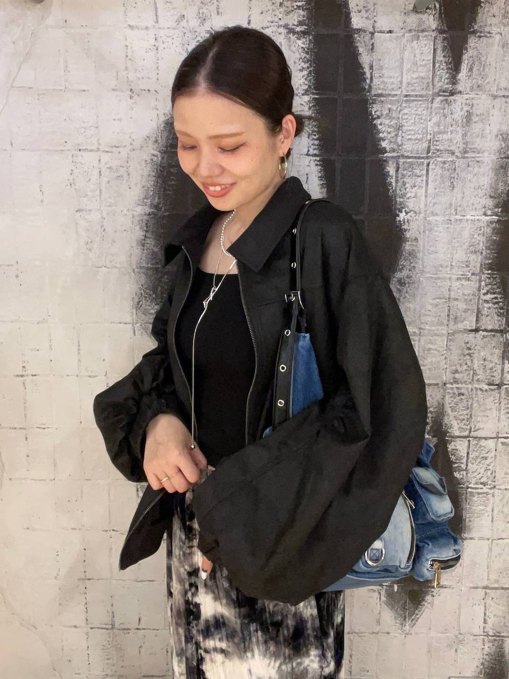 ブラック系のブルゾン、ブルー系のショルダーバッグ、ブラック系のブーツを着用したレディースの秋コーディネートの2枚目の写真