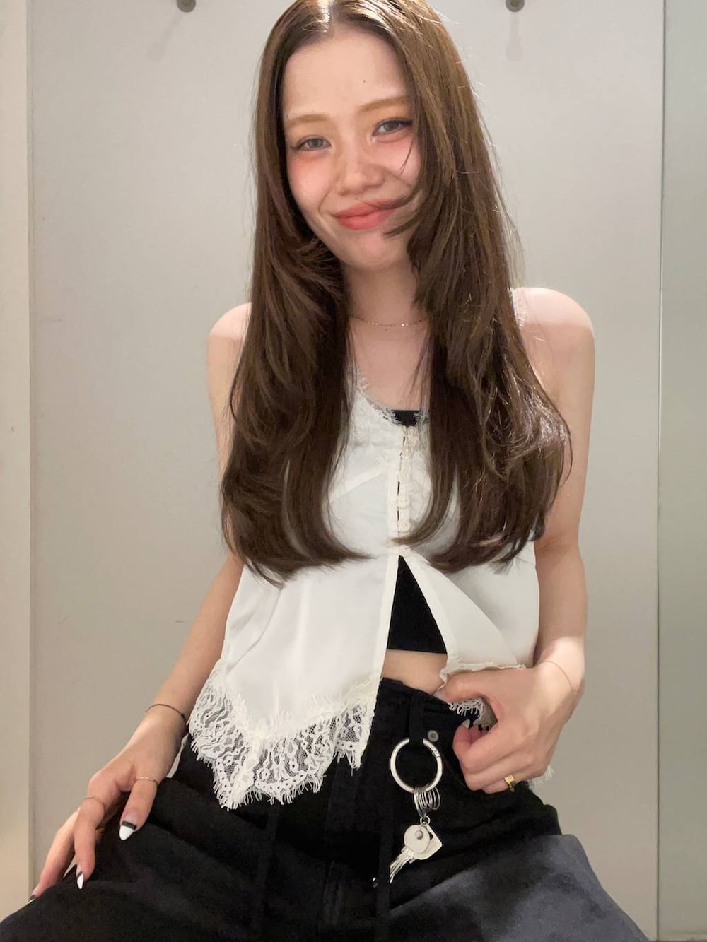 ブラック系のデニムパンツ、ホワイト系のベスト、ブラック系のベルトを着用したレディースの夏コーディネートの3枚目の写真