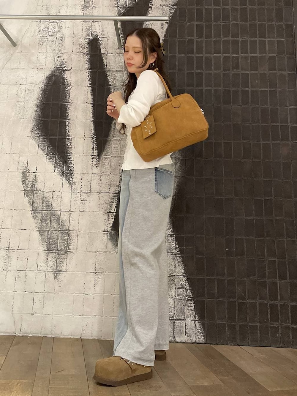 ブラウン系のボストンバッグ、ベージュ系のモカシン/デッキシューズ、ブルー系のデニムパンツを着用したレディースの春コーディネートの3枚目の写真