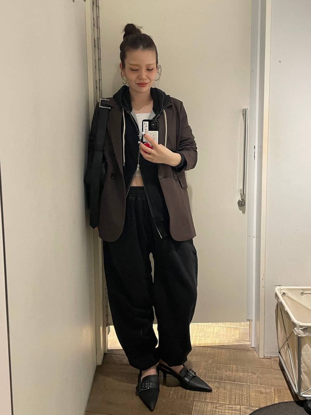 ブラック系のパーカー、ブラック系のスウェットパンツ、ホワイト系のキャミソールを着用したレディースの冬コーディネートの2枚目の写真