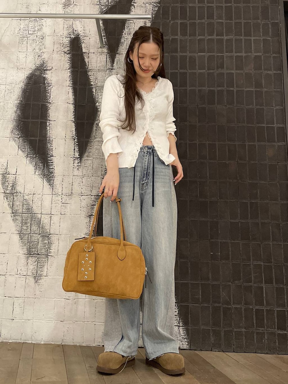 ブラウン系のボストンバッグ、ベージュ系のモカシン/デッキシューズ、ブルー系のデニムパンツを着用したレディースの春コーディネートの4枚目の写真