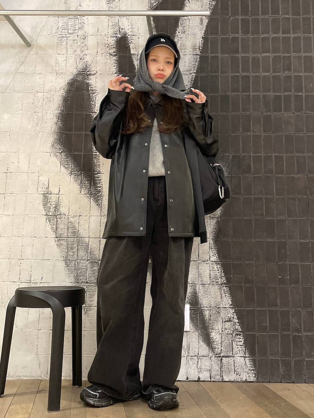 ブラック系のショルダーバッグ、グレー系のデニムパンツ、ブラック系のライダースジャケットを着用したレディースの秋コーディネートの3枚目の写真