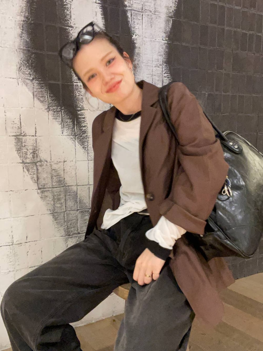 グレー系のデニムパンツ、ブラック系のボストンバッグ、ブラウン系のサンダルを着用したレディースの秋コーディネートの6枚目の写真