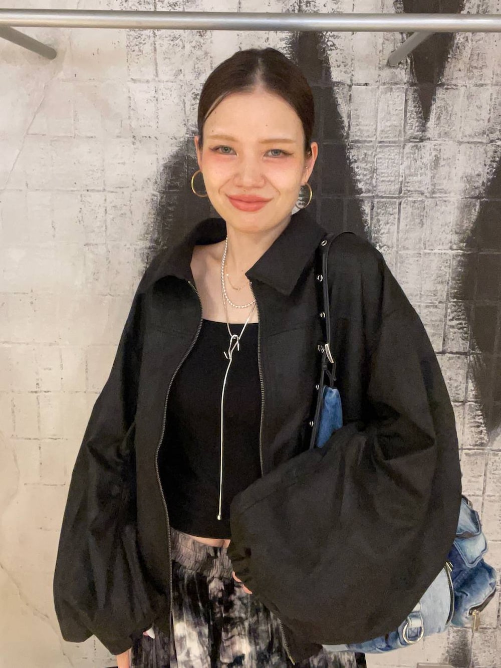 ブラック系のブルゾン、ブルー系のショルダーバッグ、ブラック系のブーツを着用したレディースの秋コーディネートの8枚目の写真