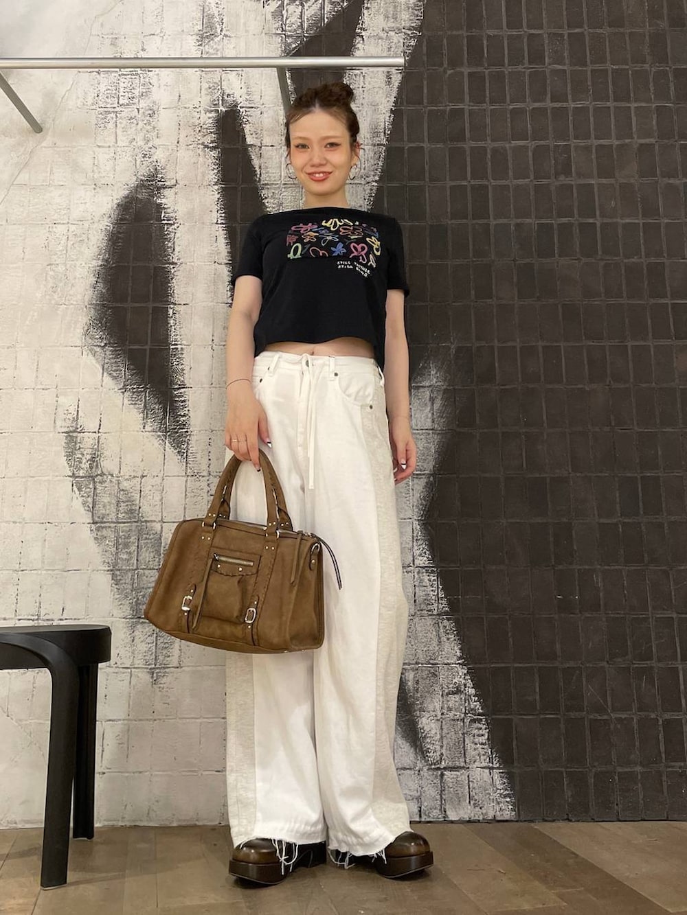 ブラック系のTシャツ/カットソー、ホワイト系のデニムパンツ、ブラウン系のボストンバッグを着用したレディースの夏コーディネートの3枚目の写真
