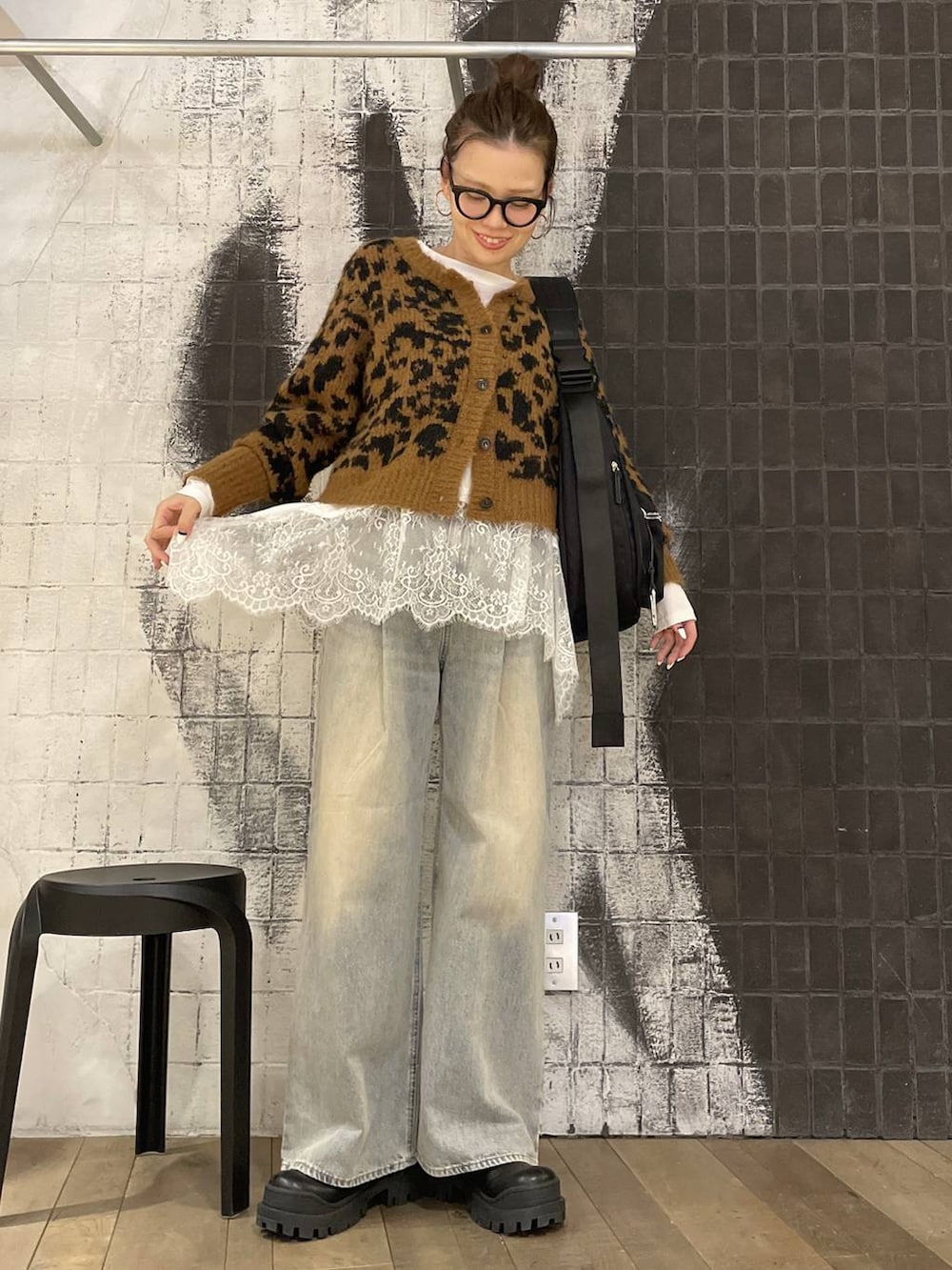 ブラック系のショルダーバッグ、ブルー系のデニムパンツ、ブラック系のブーツを着用したレディースの冬コーディネートの3枚目の写真