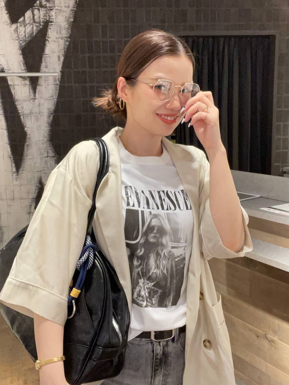 グレー系のデニムパンツ、ブラック系のボストンバッグ、ホワイト系のTシャツ/カットソーを着用したレディースの夏コーディネートの3枚目の写真