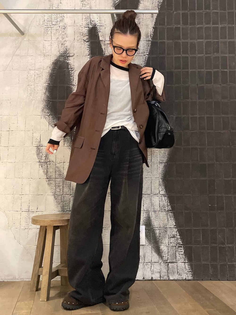 グレー系のデニムパンツ、ブラック系のボストンバッグ、ブラウン系のサンダルを着用したレディースの秋コーディネートの3枚目の写真