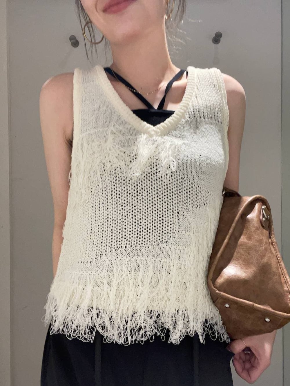 ベージュ系のモカシン/デッキシューズ、ブラウン系のボストンバッグ、ホワイト系のベストを着用したレディースの春コーディネートの3枚目の写真