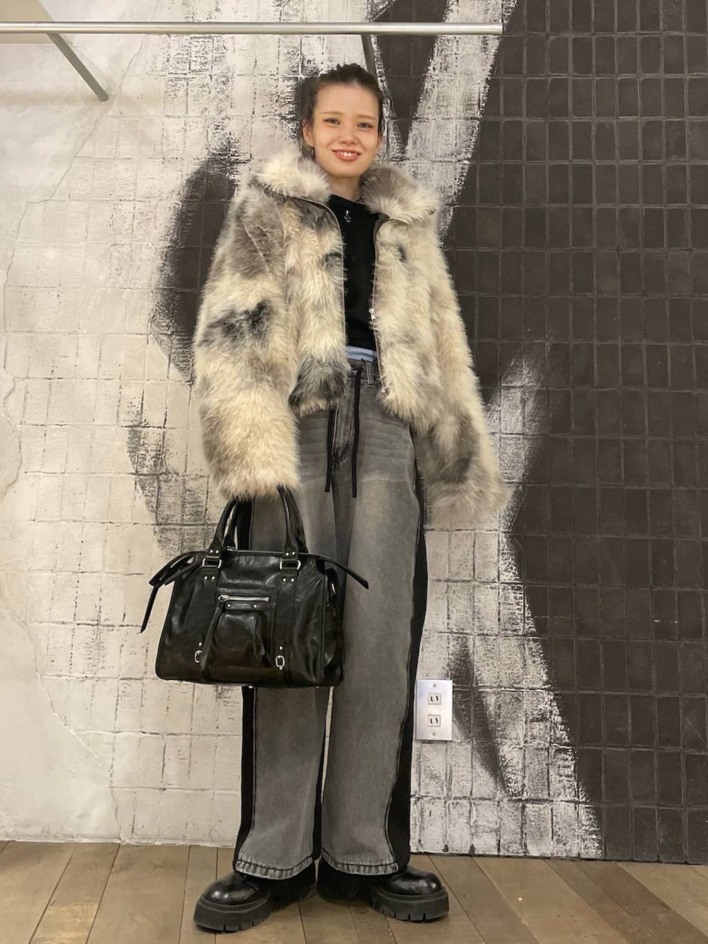 グレー系のブルゾン、ブラック系のボストンバッグ、ブラック系のデニムパンツを着用したレディースの冬コーディネートの7枚目の写真