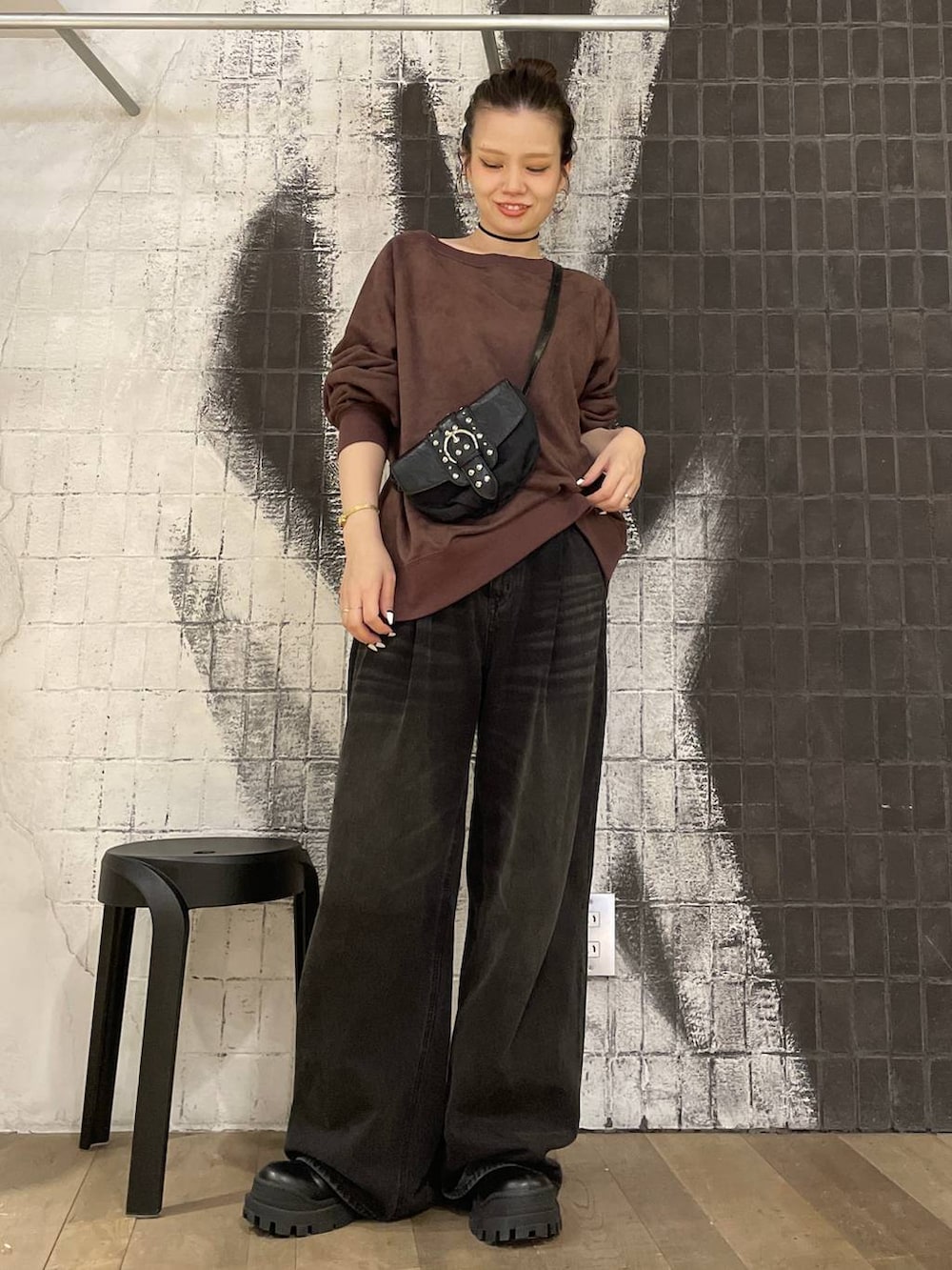 グレー系のデニムパンツ、ブラック系のショルダーバッグ、ブラック系のブーツを着用したレディースの秋コーディネートの4枚目の写真