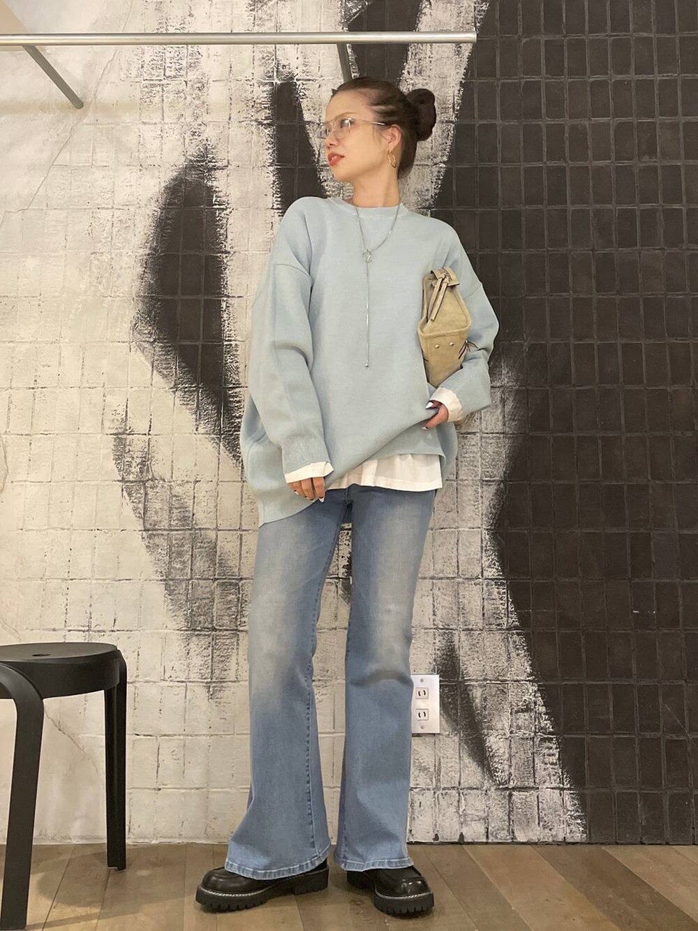 ブルー系のニット/セーター、ベージュ系のボストンバッグ、ホワイト系のTシャツ/カットソーを着用したレディースの冬コーディネートの3枚目の写真
