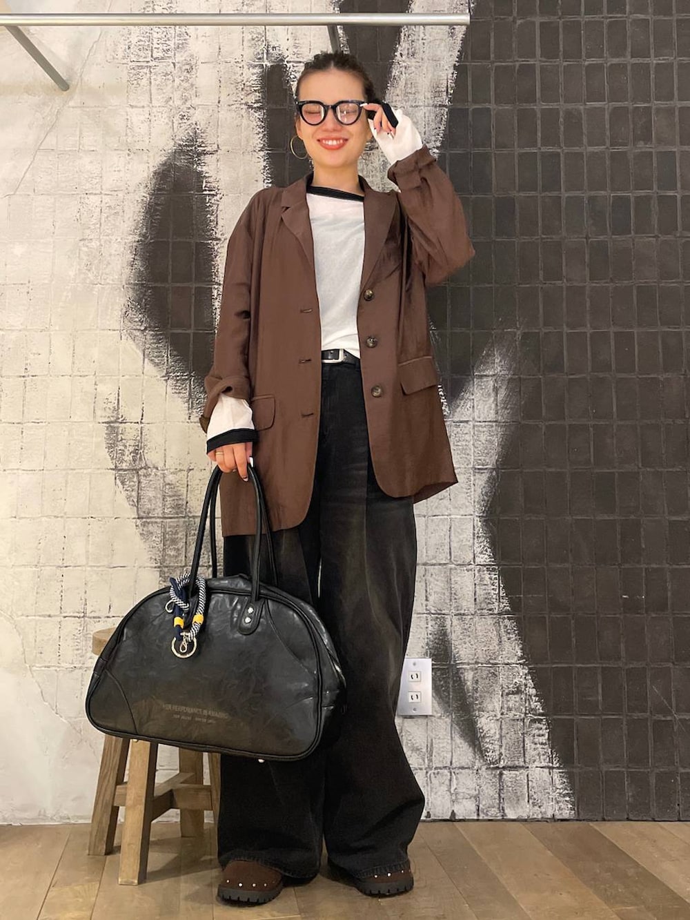 グレー系のデニムパンツ、ブラック系のボストンバッグ、ブラウン系のサンダルを着用したレディースの秋コーディネートの5枚目の写真