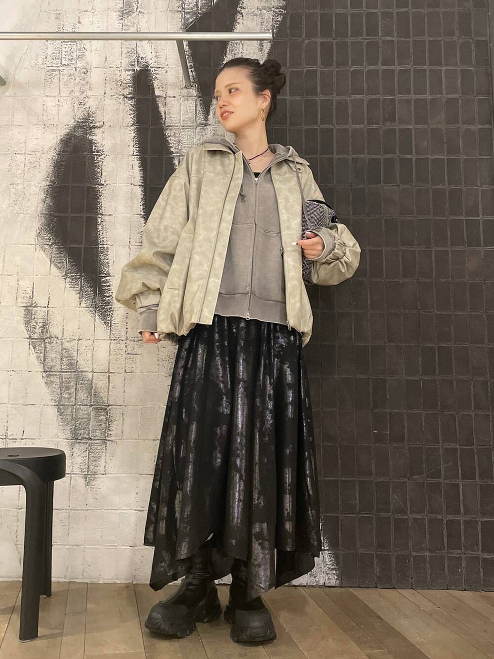 ベージュ系のブルゾン、グレー系のパーカー、ブラック系のブーツを着用したレディースの冬コーディネートの7枚目の写真