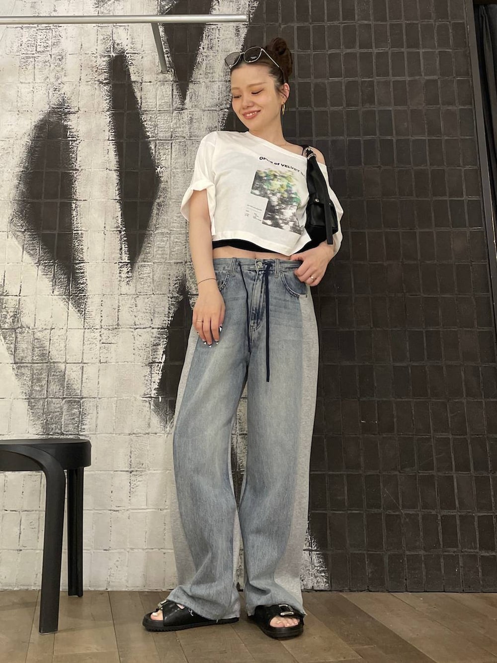 ブルー系のデニムパンツ、ブラック系のショルダーバッグ、ブラック系のサンダルを着用したレディースの夏コーディネートの3枚目の写真
